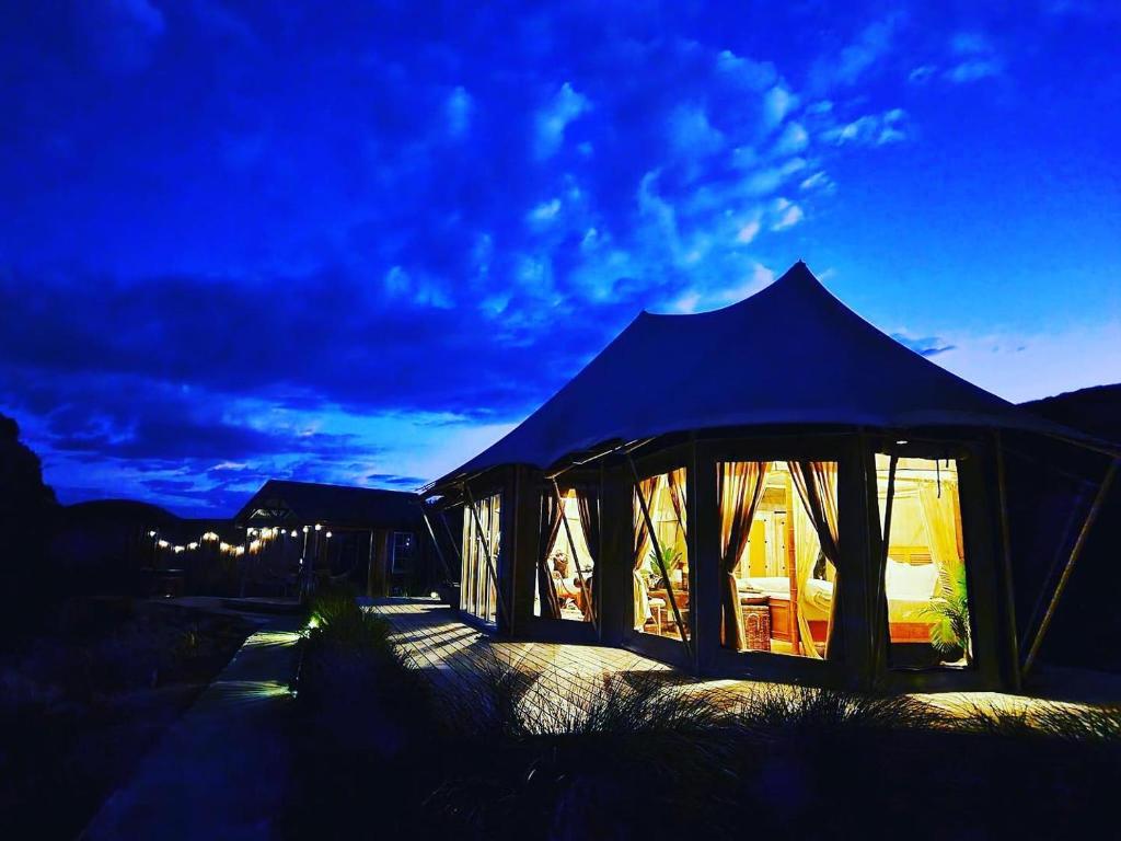 奥托罗杭阿Orchard Valley Glamping的夜晚有灯的大蓝色帐篷