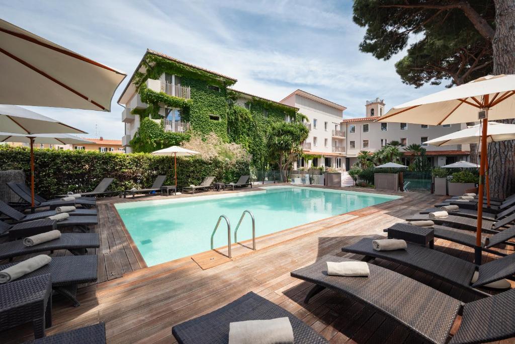 马西亚娜马里纳Marina Garden Hotel的一座带椅子和遮阳伞的游泳池位于一座建筑旁边