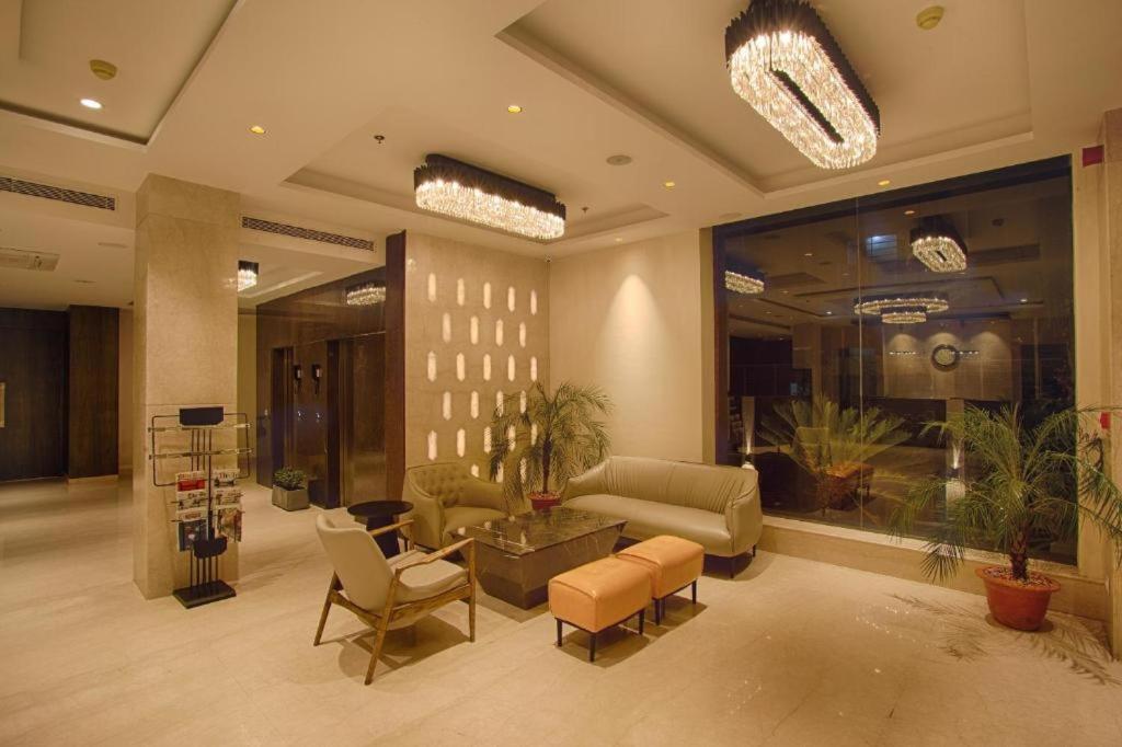 新德里Presedent Airport Hotel Near Delhi International Airport的大楼内一个带沙发和椅子的大堂
