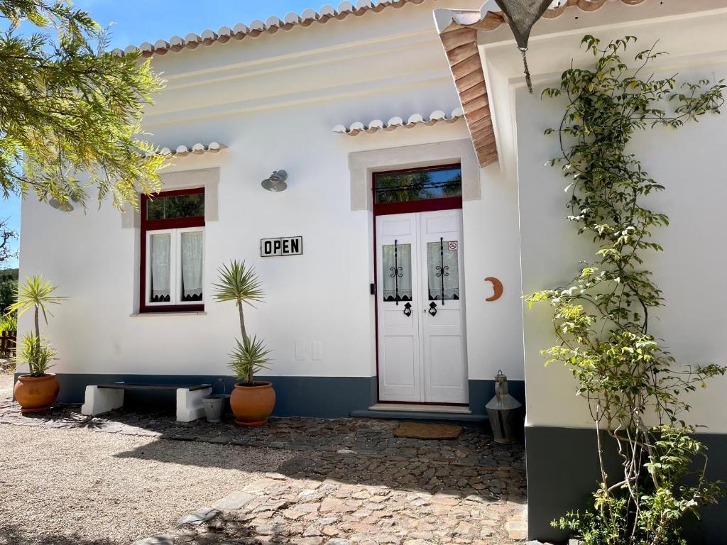 阿尔热祖尔Casa dos Cantoneiros的白色的房子,有门和盆栽植物