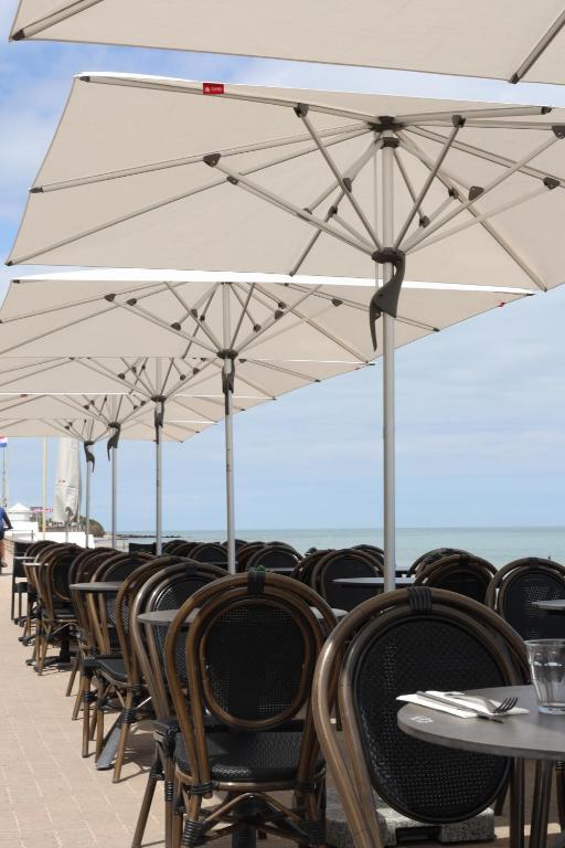 滨海圣奥班Le Clos Normand的一排配有白色遮阳伞的桌椅