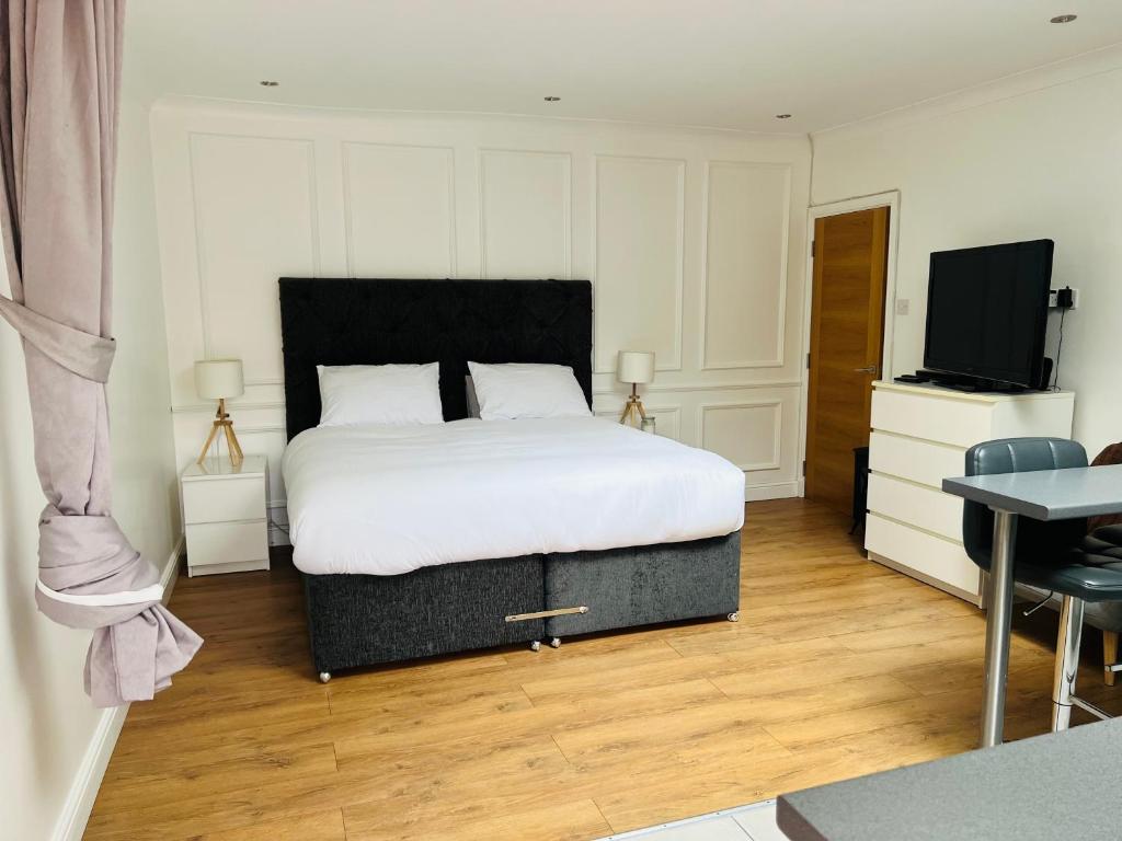 邓巴顿Whiteley’s Cottages studio的一间卧室配有一张床和一台平面电视