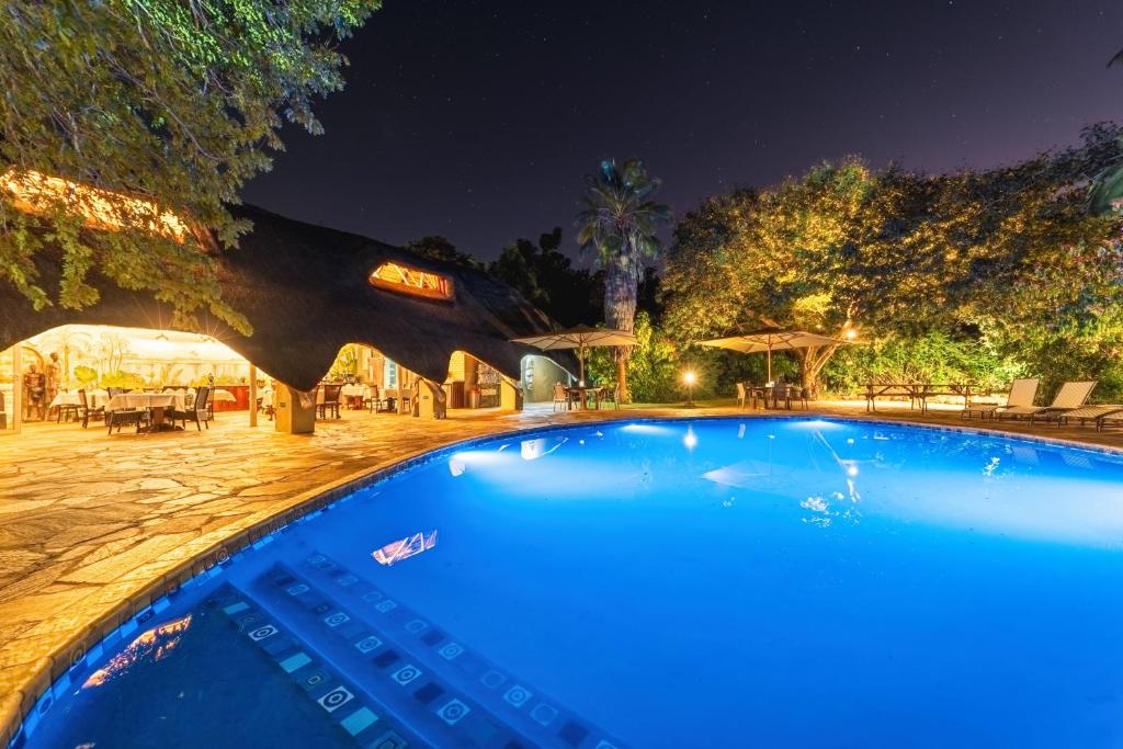 维多利亚瀑布Bayete Guest Lodge的夜间大型蓝色游泳池