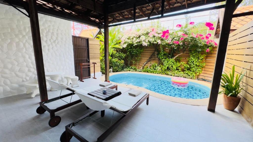 华欣BTC Boutique Resort Private Pool Villas Hua Hin บ้านทะเลจีน บูติค รีสอร์ท หัวหิน的庭院设有游泳池、桌子和椅子