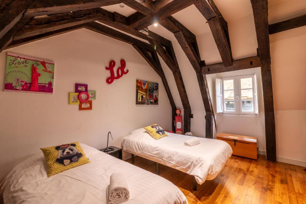 萨尔拉拉卡内达Les Chambres du "Coup de Coeur de Sarlat"的客房设有两张床和窗户。