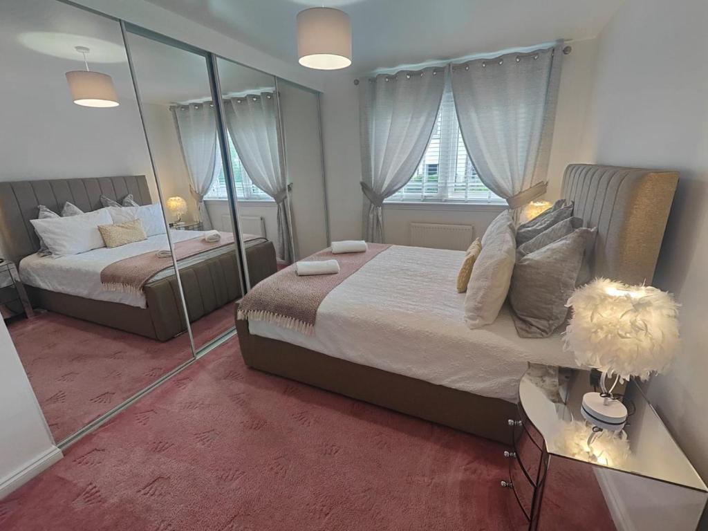 克莱德班克Lovely 2 Bedroom Modern Ground Floor Flat的一间卧室设有两张床和大镜子