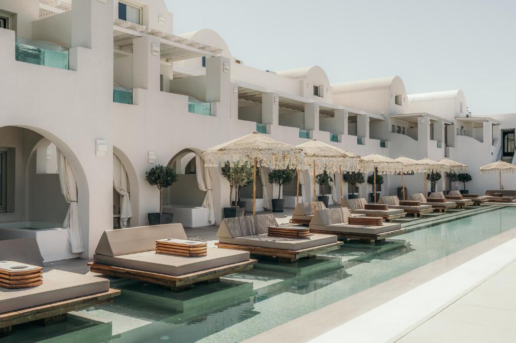费拉Apeiron Blue Santorini - Sustainable Adults Only 14 Plus的酒店游泳池设有躺椅和遮阳伞