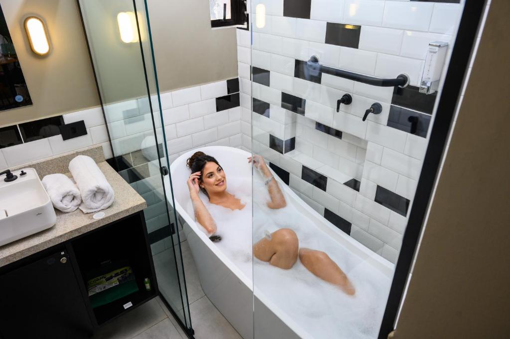隆德里纳Apto Londrina Flat Hotel jacuzzi 43 m2的妇女在浴室的浴缸里躺着