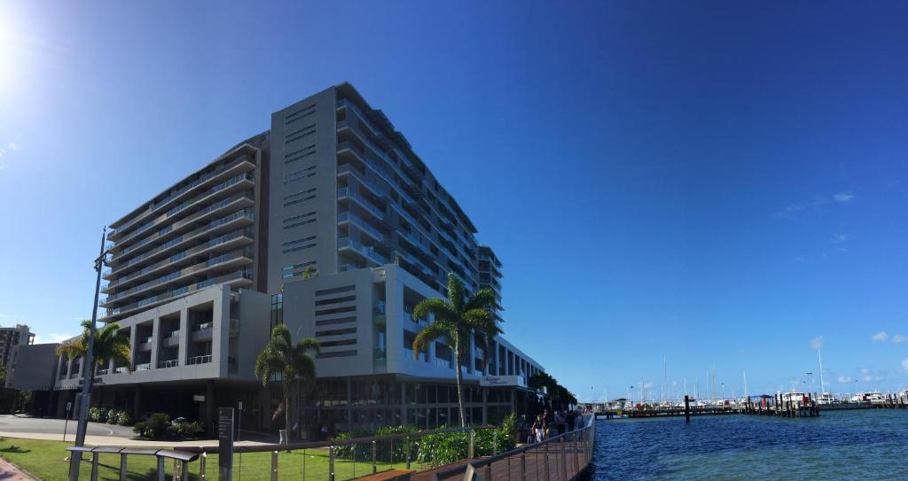 凯恩斯Cairns Private Apartments的一座高大的建筑,在水面上种有棕榈树