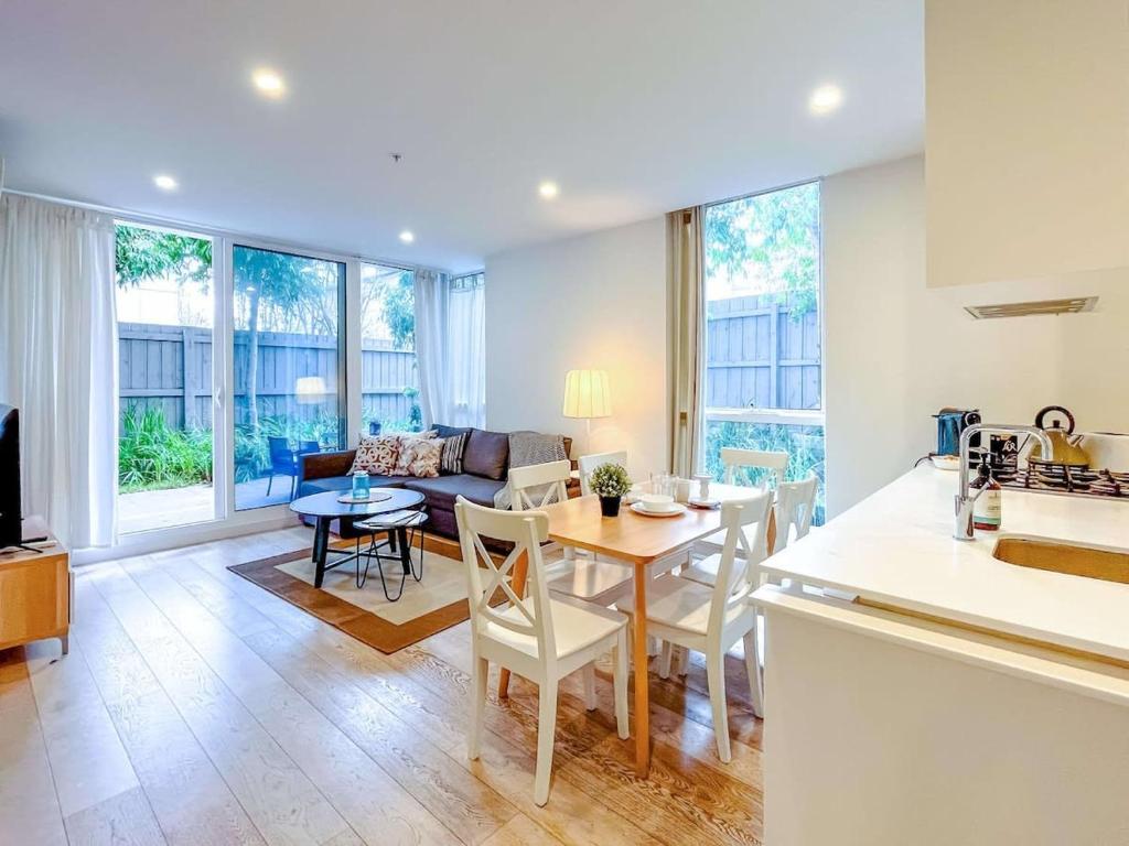 墨尔本BPM Brighton APT with Garden LG1的厨房以及带桌椅的起居室。