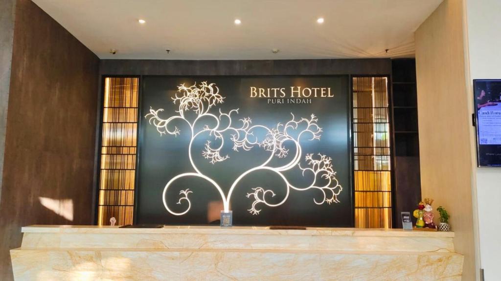 雅加达Brits Hotel Puri Indah的墙上挂着一棵树的酒店标志