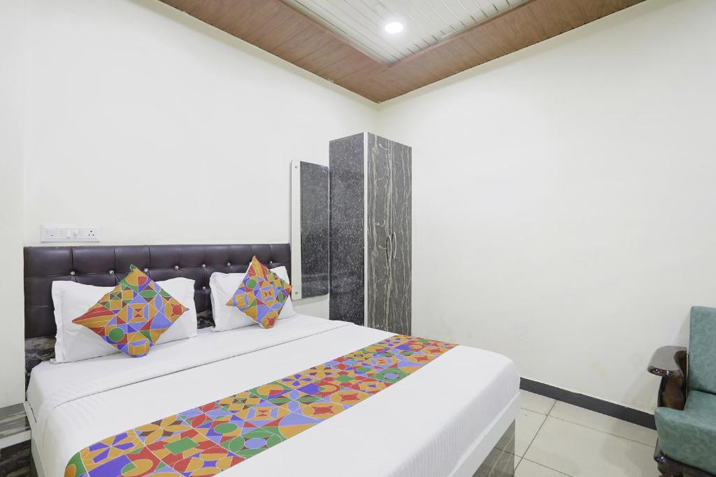 赖布尔FabExpress Sai Palace的卧室配有一张带彩色枕头的大型白色床。