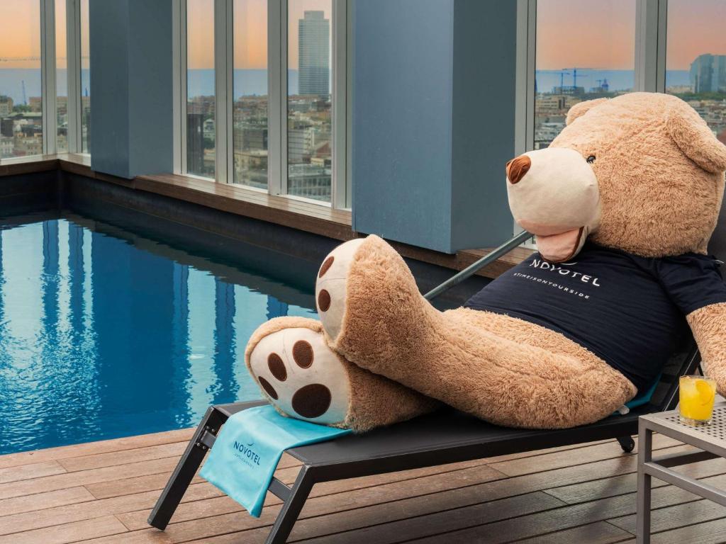 巴塞罗那诺富特巴塞罗那城市酒店的坐在泳池旁的长凳上,一只大泰迪熊