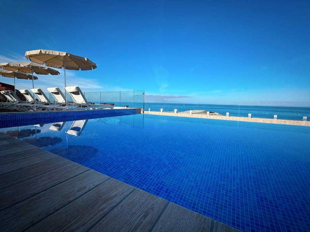 阿德耶H10阿德赫海岸皇宫酒店的一个带椅子和遮阳伞的游泳池以及大海