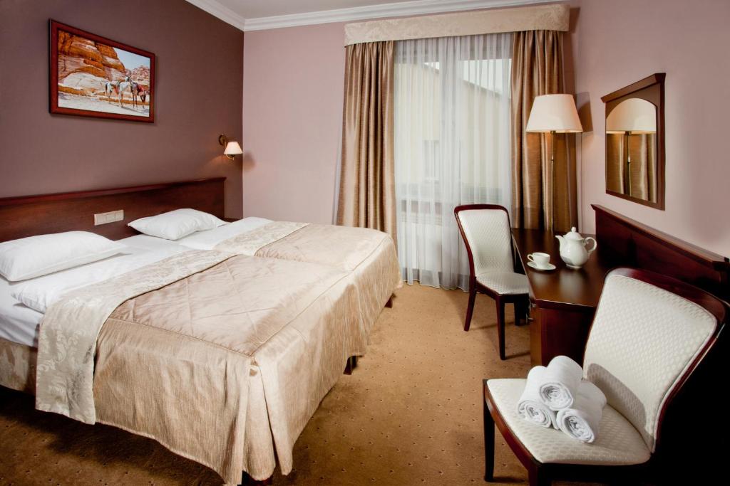 SuchowolaPensjonat Poniatowski的酒店客房带一张床、一张桌子和椅子