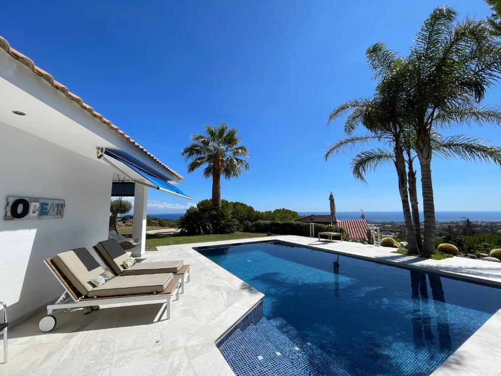 Vilassar de DaltPalm Maresme - Suite with bathroom and living-room and terrasse with ocean views in a private villa的一座别墅,设有游泳池和棕榈树