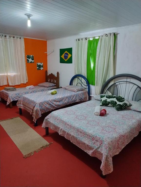 劳鲁-迪弗雷塔斯Perto Do Aeroporto De Salvador - Dona Pitanga Hostel的铺有红地毯的客房内的三张床