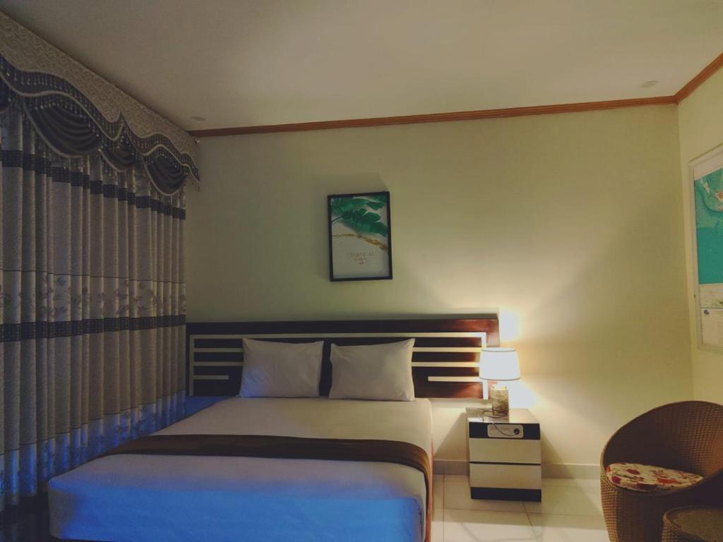 哥伦打洛省H.V HOTEL BANDARA的配有一张床和一把椅子的酒店客房