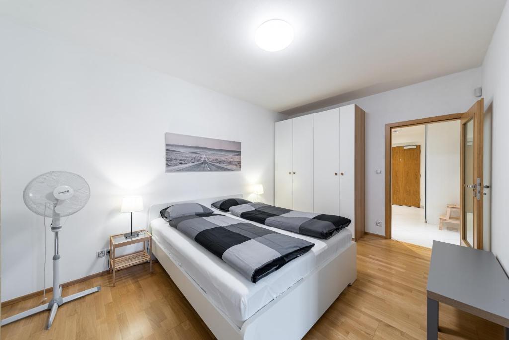 布拉格花园大厦公寓的白色卧室配有一张大床和一张书桌