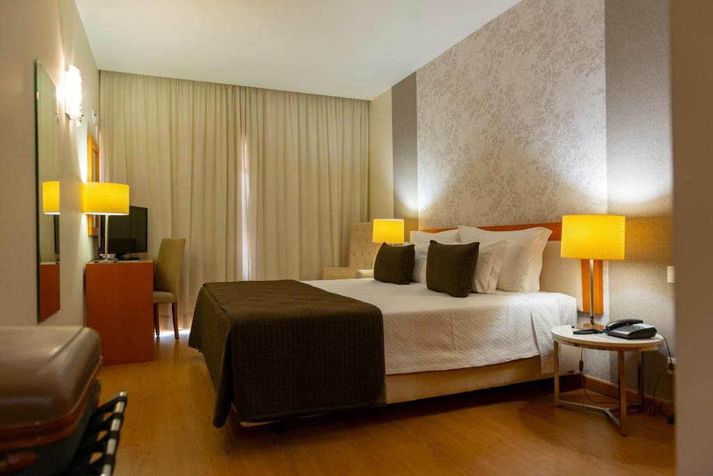 莱里亚伊欧索莱娜公寓式酒店的一间卧室配有一张带两盏灯和一把椅子的床。