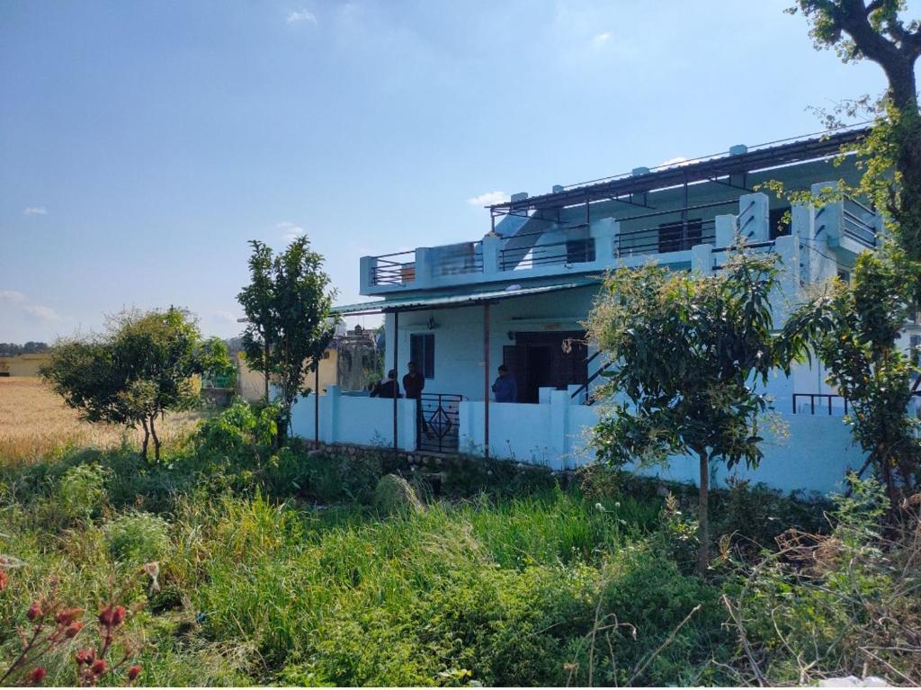 JhirnaJim Corbett Home stay的田野中间的白色房子