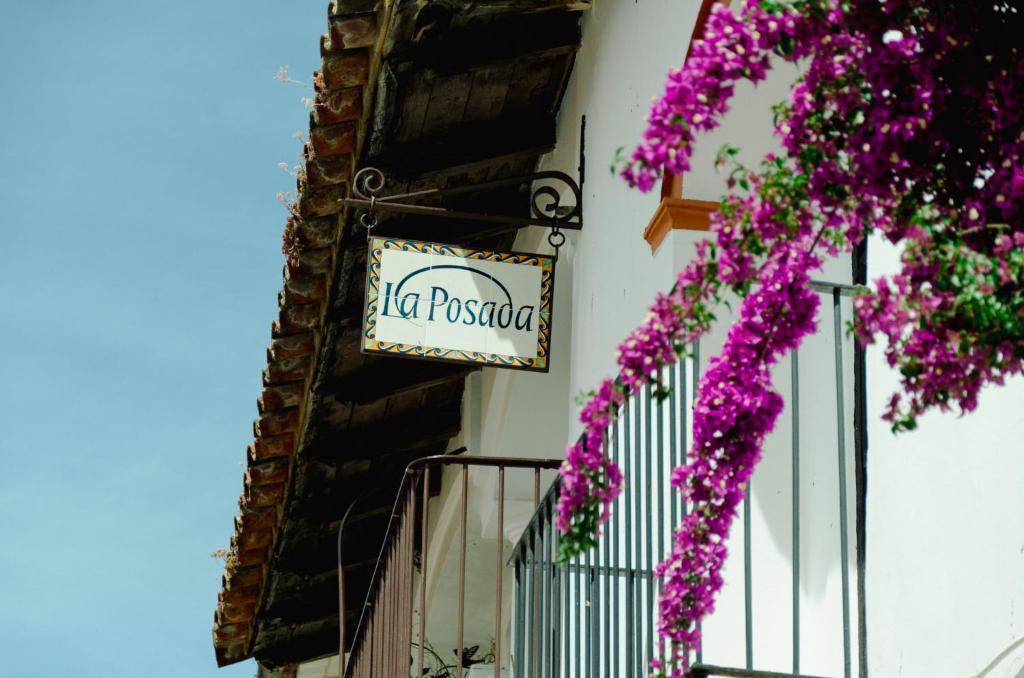 阿拉哈尔La posada de Alájar的紫色花的建筑一侧的标志