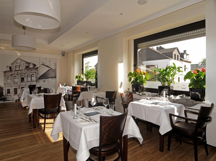Wasserliesch斯基茨酒店及餐厅的餐厅设有白色的桌椅和大窗户