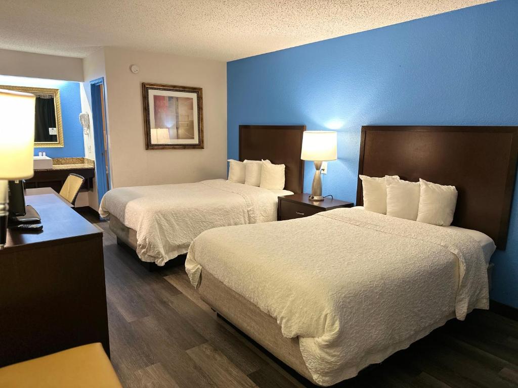 弗林特American Inn & Suites Bishop Airport Flint的两张位于酒店客房的床,拥有蓝色的墙壁