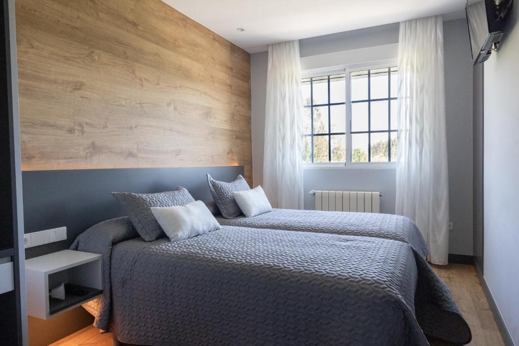 O Pino Hostal O'Cruceiro的一间卧室设有两张床和窗户。
