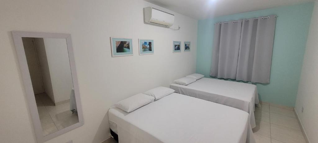 皮拉尼亚斯Aquarela do Sertão的白色的客房配有两张床和镜子