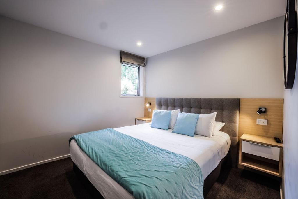 蒂阿瑙Tasman Holiday Parks - Te Anau的一间卧室配有一张带蓝色枕头的大床