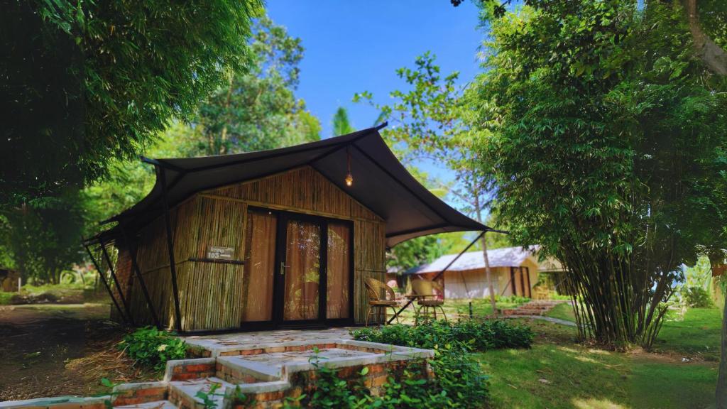 拉古洼"D'BAMBOO KAMP" Desa Wisata Ekang的一间黑色屋顶的小小屋