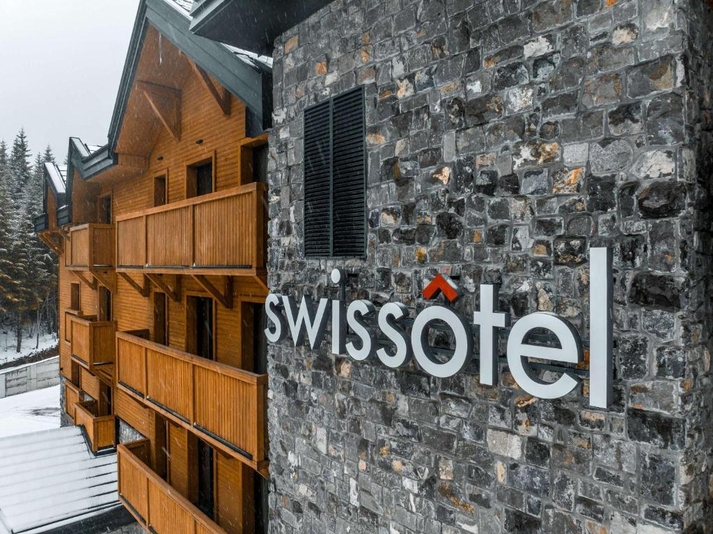 科拉欣Swissôtel Resort Kolasin的一面有伊索特标志的石头建筑