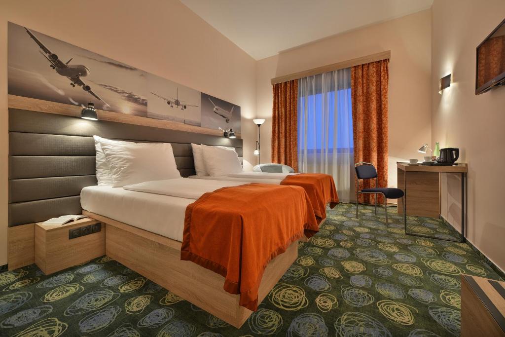 布拉格华美达布拉格机场酒店的酒店客房,配有一张带橙色床单的大床