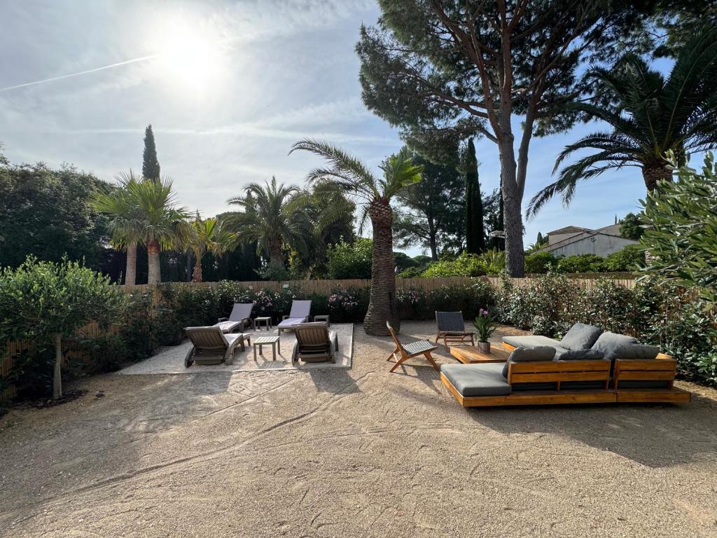 滨海卡瓦莱尔Appartement 3ch avec terrasse et jardin à 400m de la plage的一个带沙发和椅子的庭院,并种植了棕榈树。