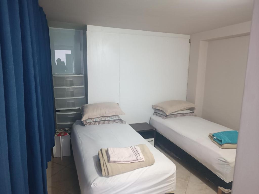 库里提巴Assel Pousada Botanico的小房间设有两张床,配有蓝色窗帘
