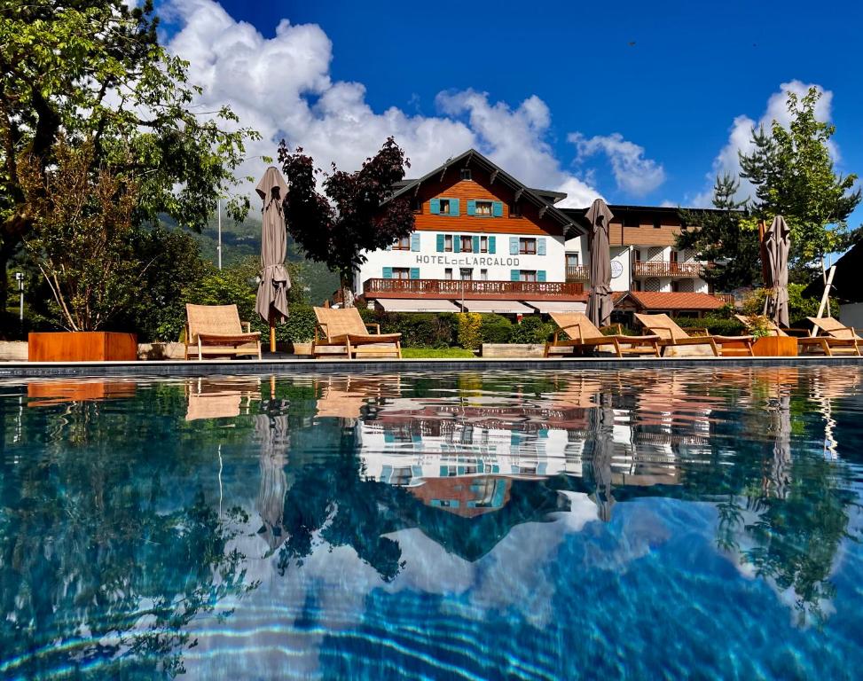 杜萨尔L'Arcalod Lac d'Annecy - Hôtel Restaurant & Spa的一个带椅子的游泳池和一个背景房子
