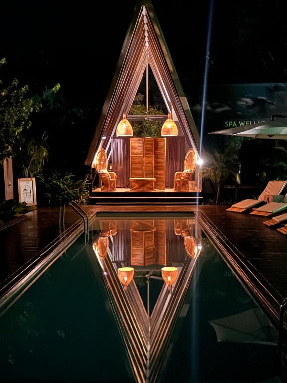 别霍港Namu Garden Hotel & Spa的一座小房子在晚上被映入游泳池