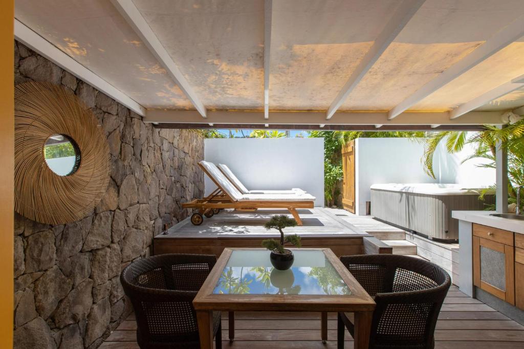 Saint BarthelemyCharming bungalow in Saint Barthelemy with shared pool的石墙上配有桌椅的庭院