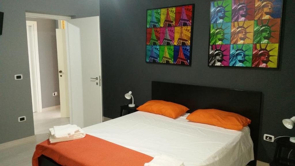 塞利亚马里纳B&B Colors的一间卧室配有一张带橙色枕头的床,墙上挂有绘画作品