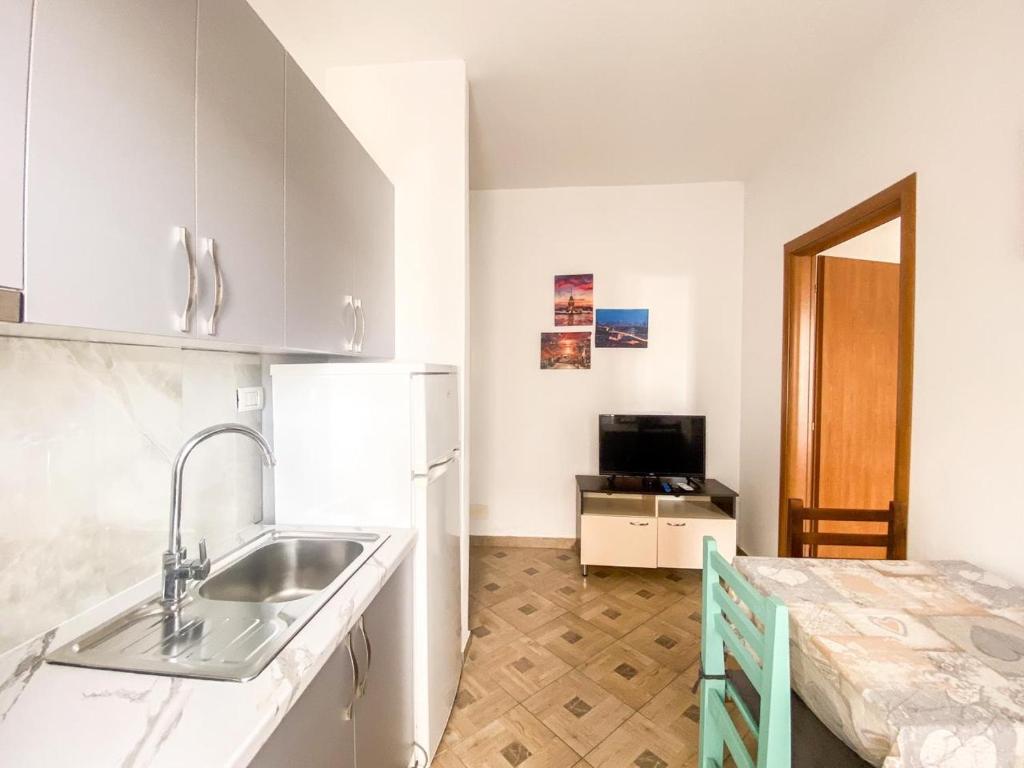 都拉斯LunaSol seaside Apartments的厨房配有白色橱柜、水槽和桌子