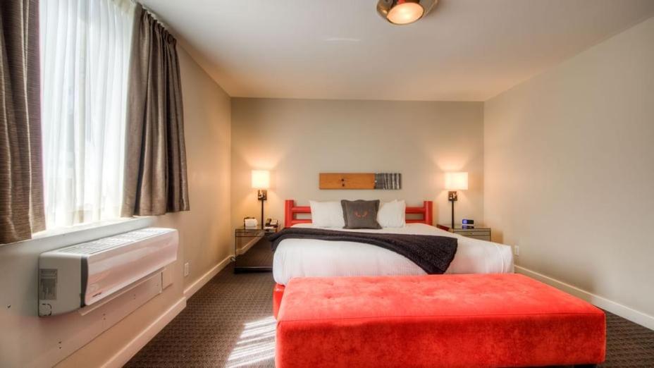 惠斯勒阿达拉酒店的酒店客房带一张床和一个红色的搁脚凳