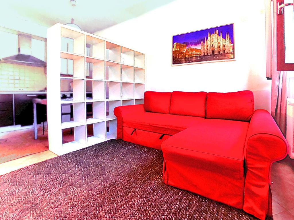 米兰L' appartamento sul Naviglio的客厅里一张红色的沙发,配有桌子