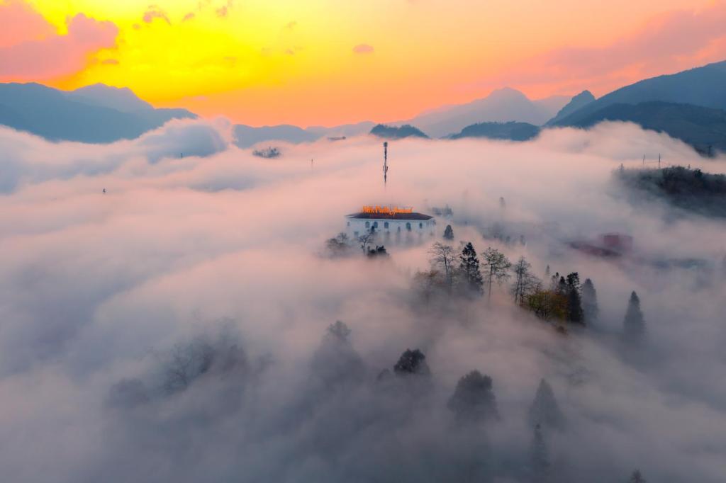 萨帕Silk Path Grand Sapa Resort & Spa的日落时分在云中望塔