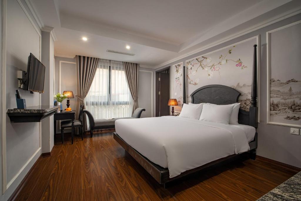 河内Amara Hanoi Hotel的卧室配有一张白色大床和一张书桌