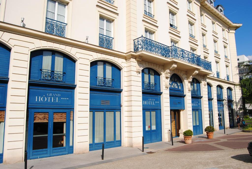 勒普莱西罗班松格朗德公寓大酒店的街道上设有蓝色门窗的建筑