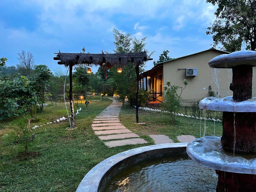 塔拉Grand Narmada Homestay Resort-Bandhavgarh的一座花园,房子前方有一个喷泉