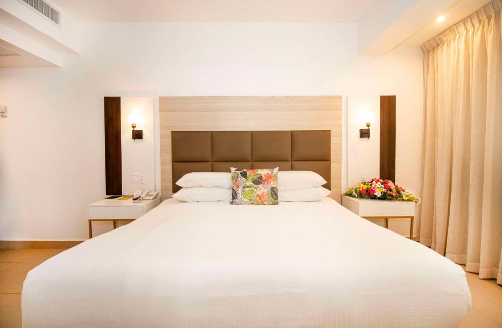 巴拿马城Hotel Faranda Express Soloy and Casino, a member of Radisson Individuals的卧室配有一张白色的大床和两张桌子