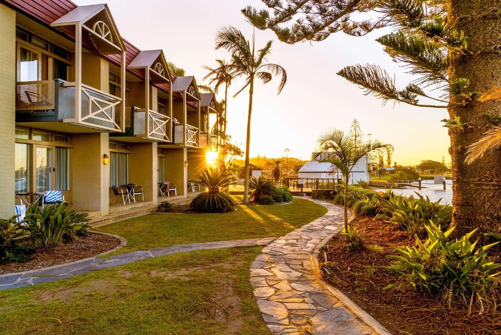 麦夸里港Comfort Resort Waters Edge的棕榈树和步道的度假村