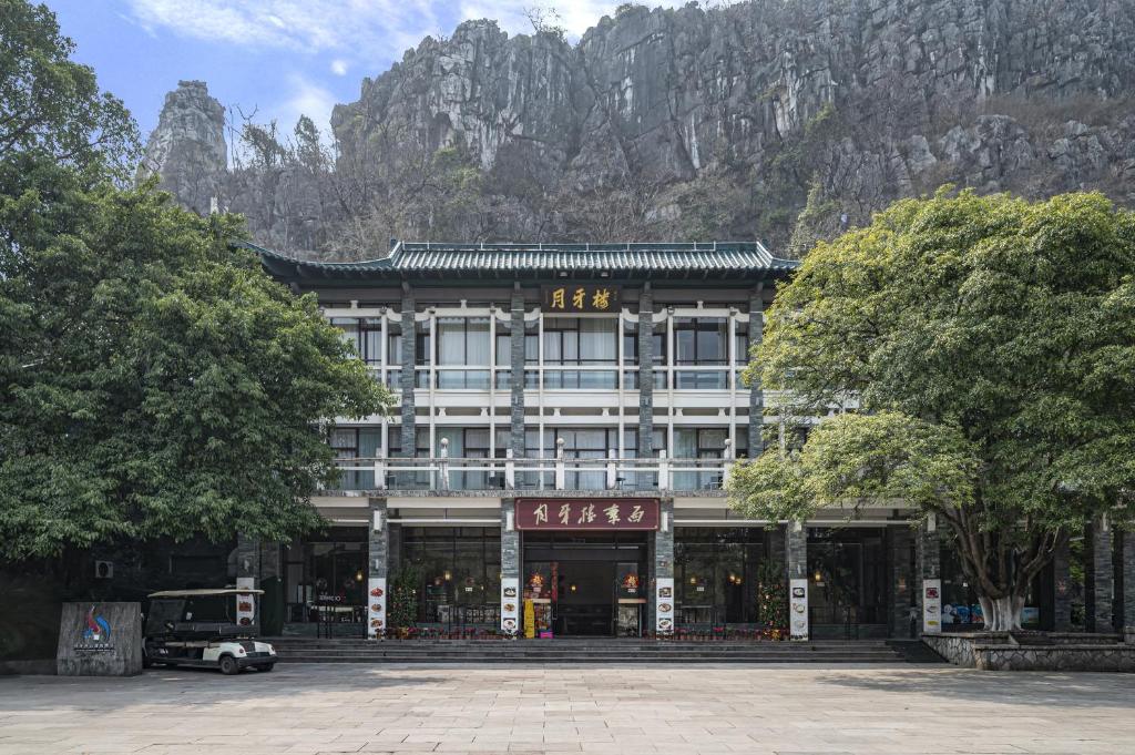 桂林桂林月牙楼伴山度假酒店的山前的一座建筑,前面有树木